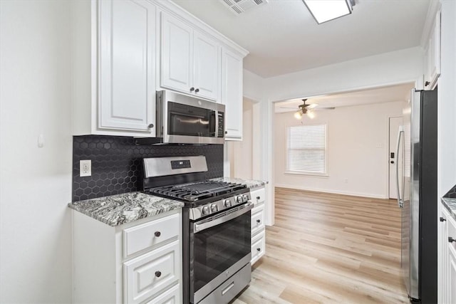 kitchen featuring light stone counters, stainless steel appliances, tasteful backsplash, white cabinetry, and ceiling fan