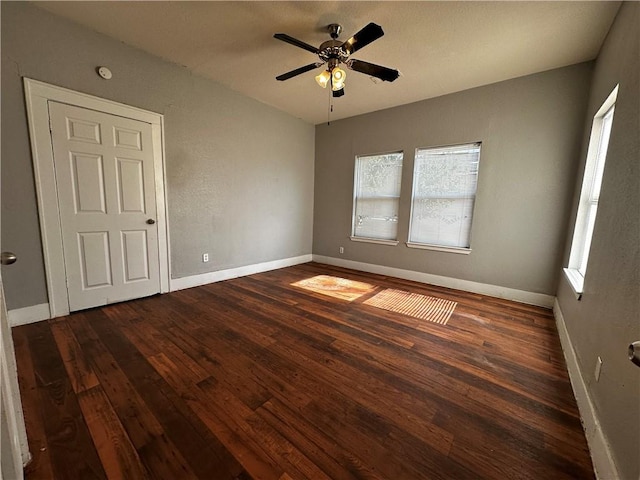 unfurnished room featuring ceiling fan, dark wood finished floors, and baseboards