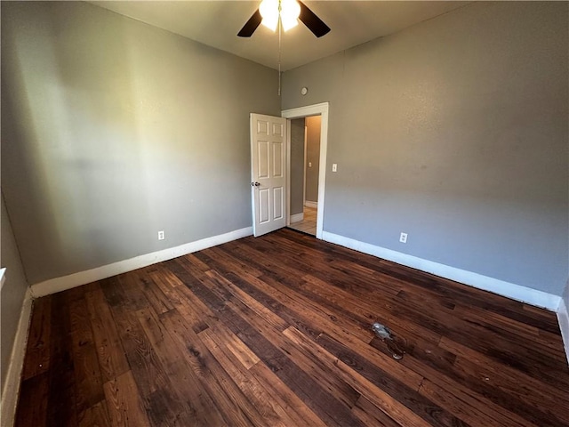 unfurnished room featuring dark wood-style floors, a ceiling fan, and baseboards