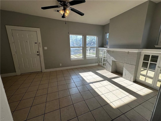 unfurnished living room with light tile patterned floors, a ceiling fan, visible vents, baseboards, and a brick fireplace