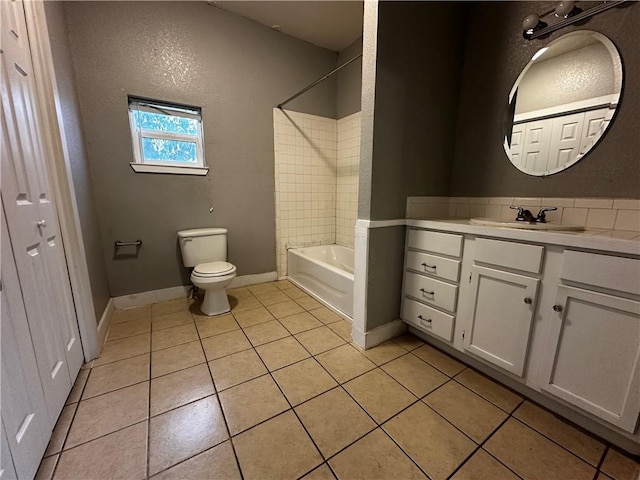 bathroom featuring bathing tub / shower combination, toilet, vanity, baseboards, and tile patterned floors