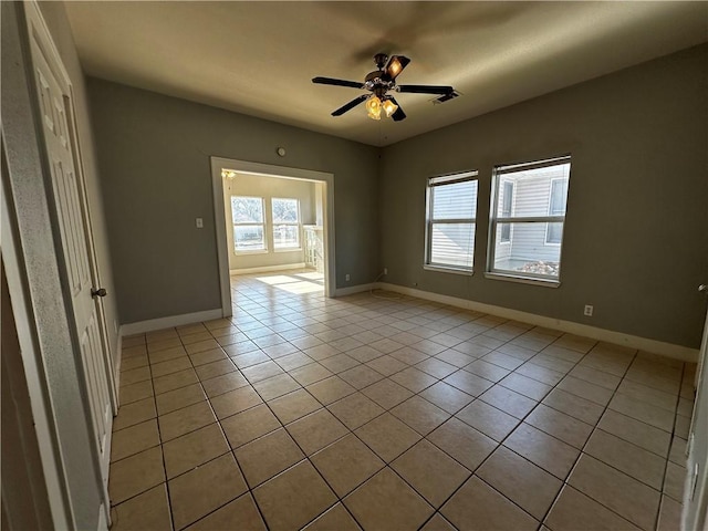 empty room with light tile patterned floors, ceiling fan, and baseboards