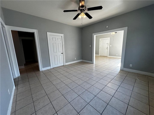 unfurnished bedroom featuring light tile patterned floors, baseboards, and a ceiling fan