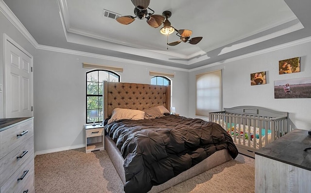 bedroom with a tray ceiling, ceiling fan, crown molding, and light carpet