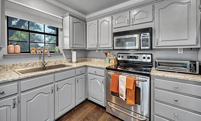 kitchen with sink, dark hardwood / wood-style floors, gray cabinets, ornamental molding, and stainless steel appliances