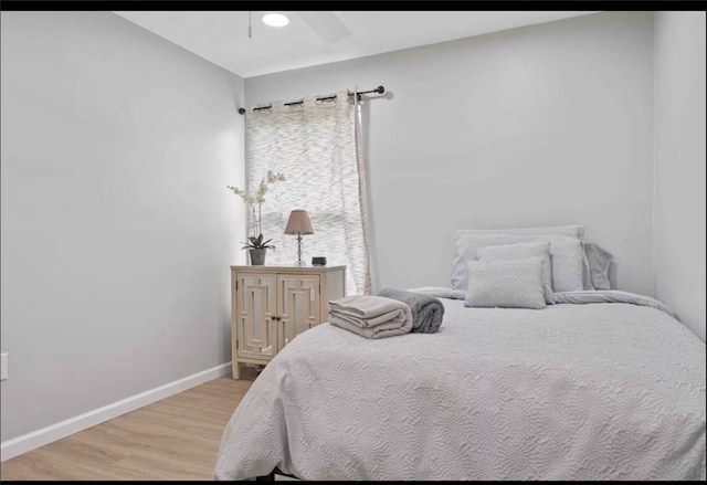 bedroom featuring ceiling fan, baseboards, and wood finished floors