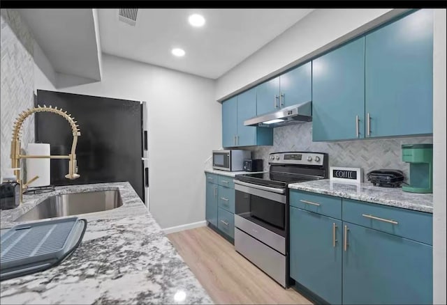 kitchen featuring blue cabinets, light wood-style floors, under cabinet range hood, and stainless steel appliances