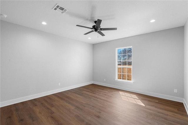 spare room featuring dark wood-style flooring, visible vents, ceiling fan, and baseboards