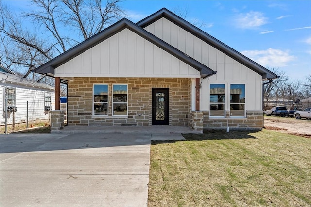 view of front of home featuring stone siding, board and batten siding, and a front yard