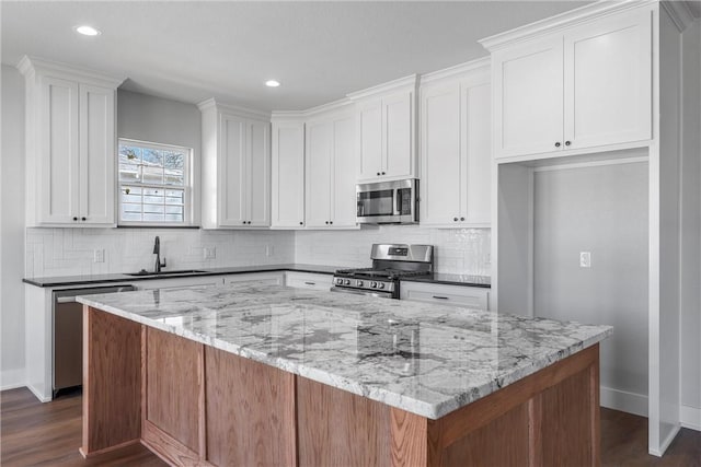 kitchen with appliances with stainless steel finishes, a sink, a center island, and decorative backsplash