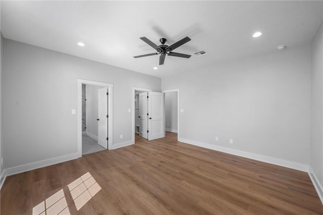 unfurnished bedroom featuring baseboards, visible vents, wood finished floors, a walk in closet, and recessed lighting