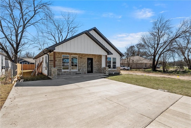 view of front of home featuring concrete driveway, a front lawn, board and batten siding, and fence