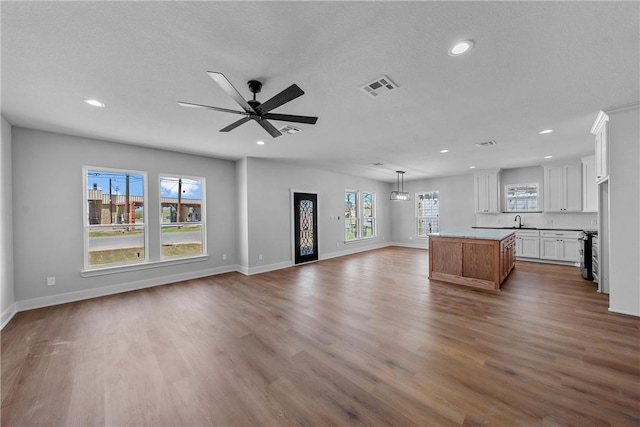 unfurnished living room featuring baseboards, visible vents, dark wood finished floors, and a sink