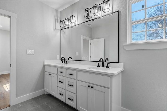 full bath featuring double vanity, baseboards, a sink, and tile patterned floors