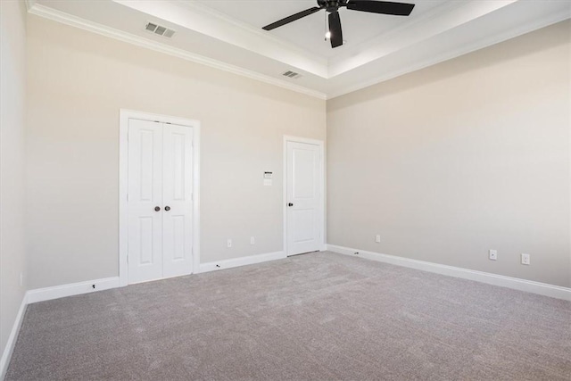 carpeted empty room with a raised ceiling, crown molding, and ceiling fan