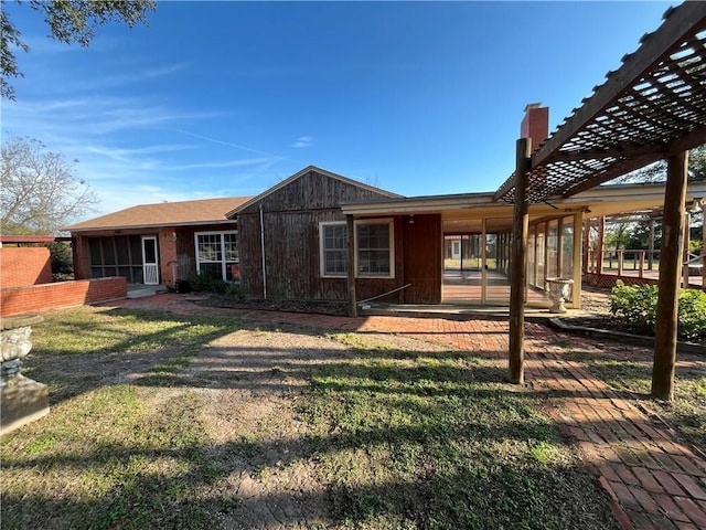 back of house featuring a pergola and a lawn