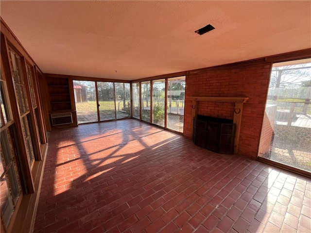 unfurnished sunroom with an AC wall unit and a fireplace