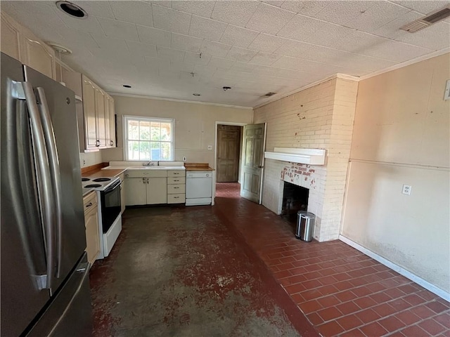 kitchen with sink, white appliances, cream cabinetry, a fireplace, and ornamental molding