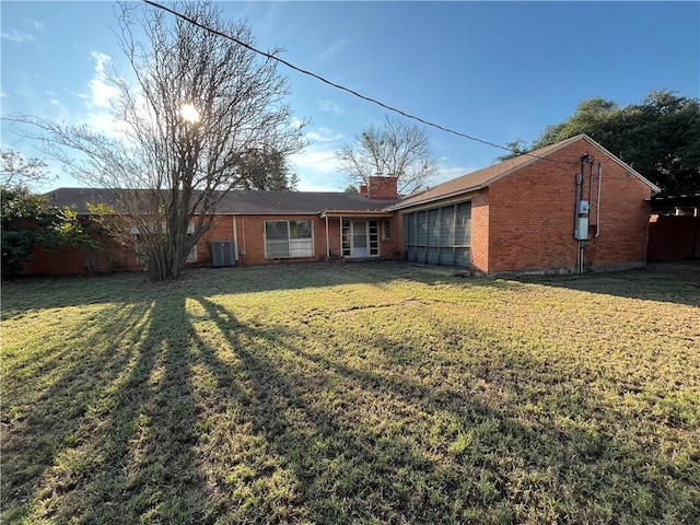 rear view of house featuring central AC and a yard