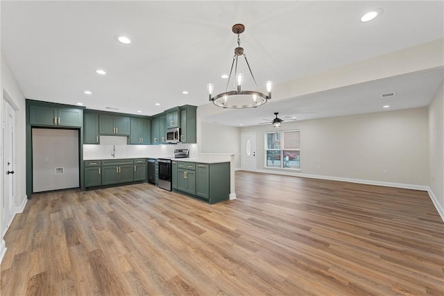 kitchen with hanging light fixtures, appliances with stainless steel finishes, light hardwood / wood-style floors, green cabinets, and ceiling fan with notable chandelier