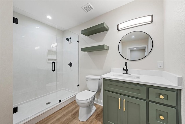 bathroom with wood-type flooring, vanity, toilet, and a shower with door