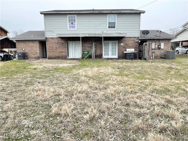 rear view of house with central air condition unit and a lawn