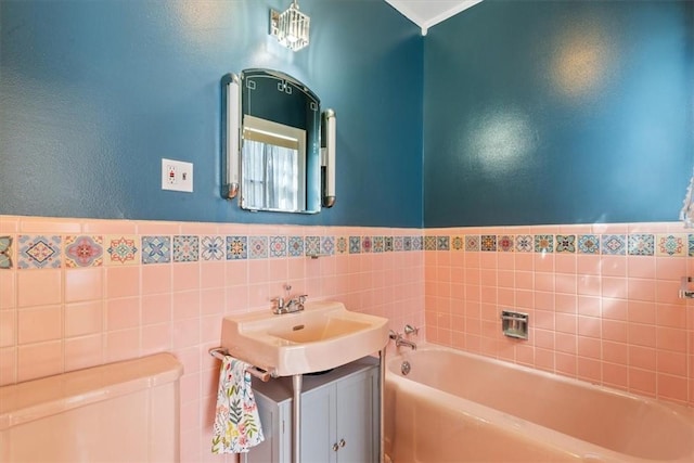 bathroom with vanity, toilet, wainscoting, tile walls, and a bath