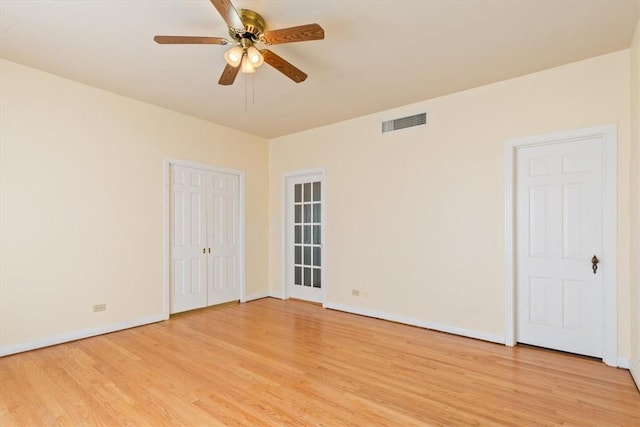 unfurnished room featuring light wood finished floors, visible vents, baseboards, and a ceiling fan