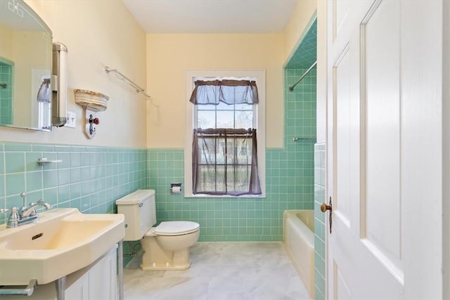 full bathroom featuring toilet, shower / bathing tub combination, tile walls, wainscoting, and vanity