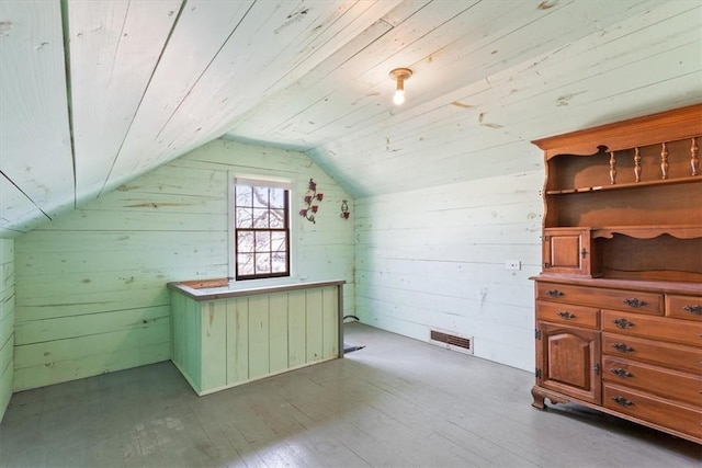 additional living space with hardwood / wood-style floors, wooden walls, visible vents, vaulted ceiling, and wood ceiling