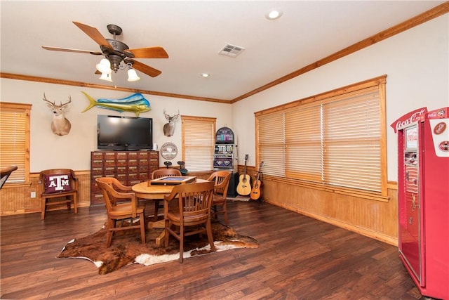 dining space with dark hardwood / wood-style flooring, wooden walls, ceiling fan, and crown molding