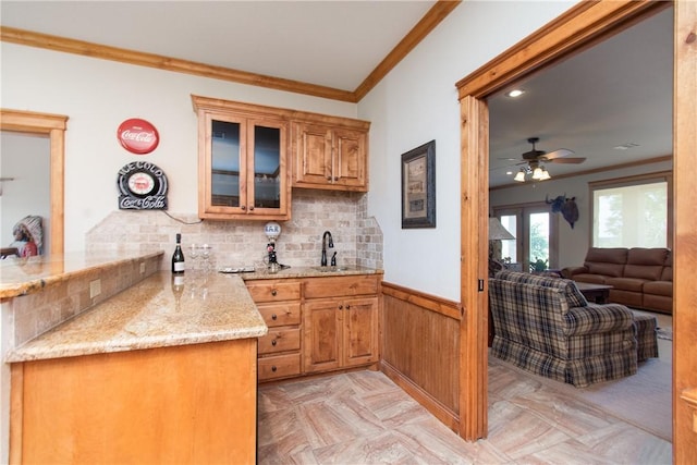 kitchen featuring light stone countertops, kitchen peninsula, sink, and tasteful backsplash