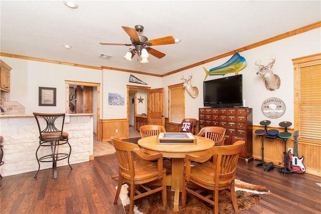 dining area featuring dark hardwood / wood-style flooring, wooden walls, ceiling fan, and ornamental molding