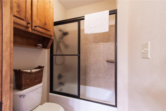 bathroom with toilet and bath / shower combo with glass door