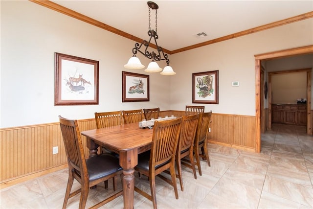 dining area with ornamental molding and wood walls