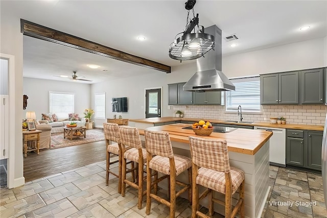 kitchen featuring a kitchen breakfast bar, dishwasher, hanging light fixtures, island exhaust hood, and butcher block counters