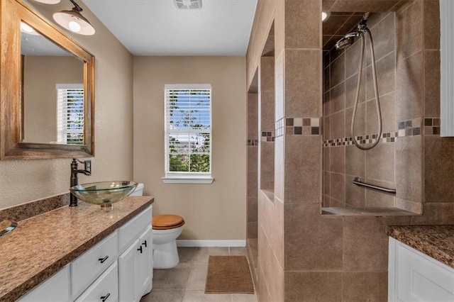 bathroom with a wealth of natural light, tile patterned flooring, vanity, and tiled shower