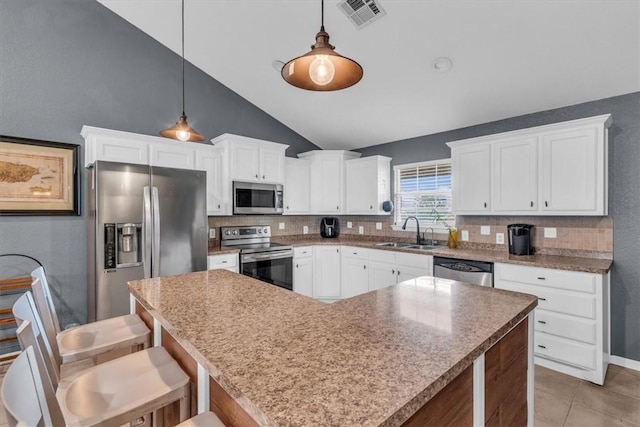 kitchen with decorative light fixtures, a kitchen island, sink, and stainless steel appliances