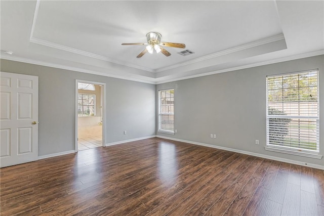 empty room featuring dark hardwood / wood-style flooring, a tray ceiling, and plenty of natural light