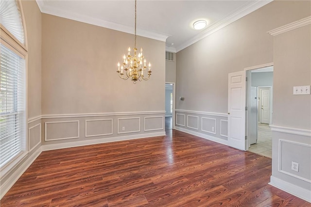 empty room with crown molding, a notable chandelier, and hardwood / wood-style flooring