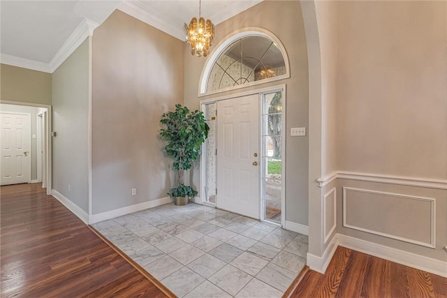 entrance foyer featuring a healthy amount of sunlight, light wood-type flooring, ornamental molding, and a chandelier