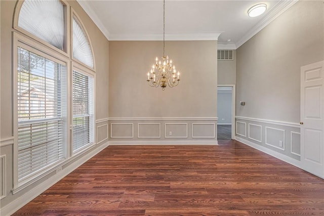 spare room featuring crown molding, dark wood-type flooring, and a notable chandelier