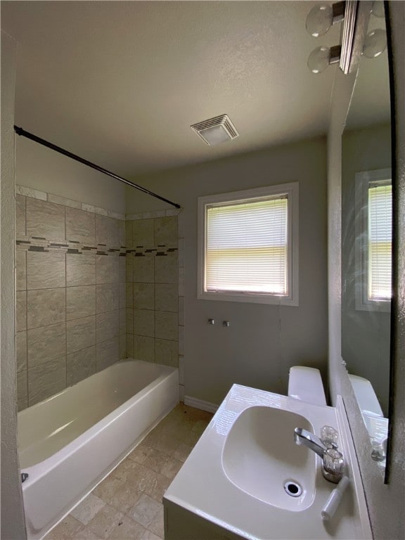 full bathroom with toilet, sink, and tiled shower / bath