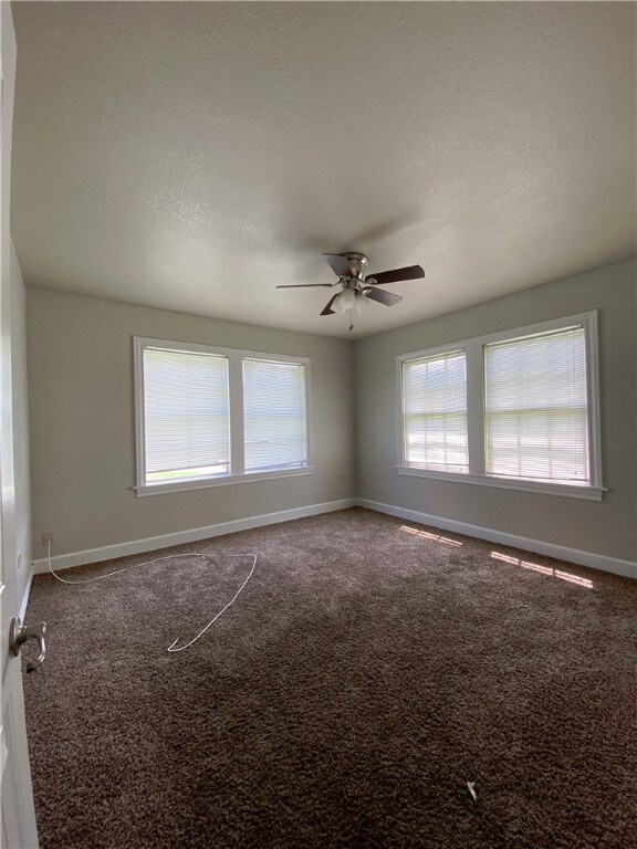 unfurnished room featuring ceiling fan, carpet floors, and a textured ceiling