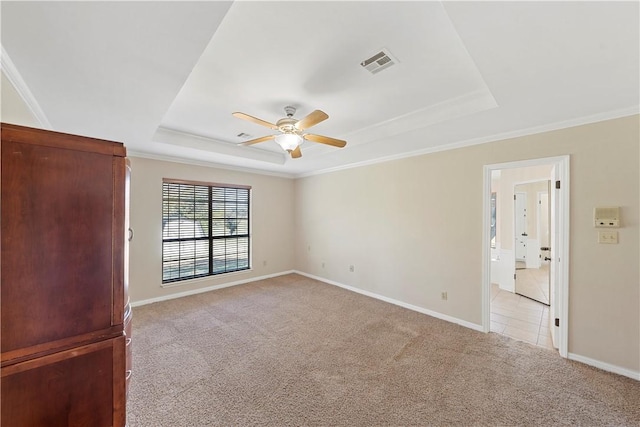 carpeted empty room featuring a raised ceiling, ceiling fan, and ornamental molding