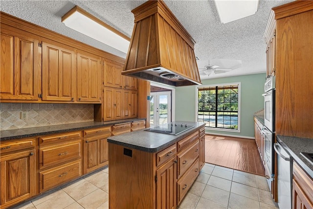 kitchen featuring premium range hood, ceiling fan, black electric stovetop, and light tile patterned flooring