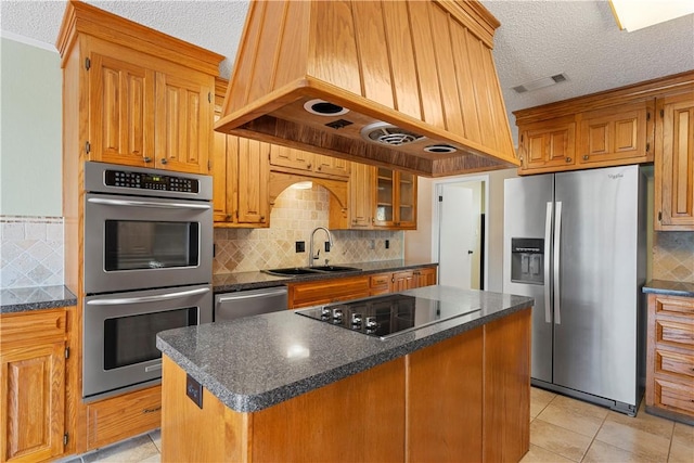 kitchen with appliances with stainless steel finishes, premium range hood, a textured ceiling, sink, and a kitchen island