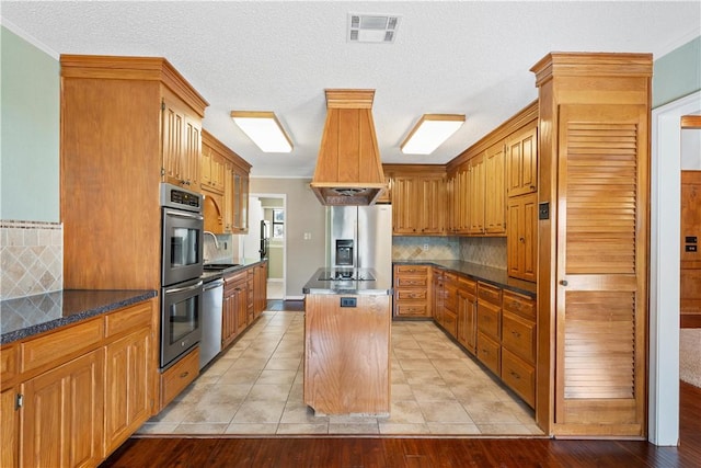 kitchen with a center island, tasteful backsplash, light hardwood / wood-style flooring, and stainless steel appliances