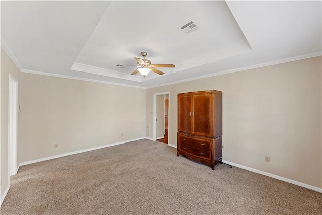 unfurnished bedroom featuring a raised ceiling, ceiling fan, crown molding, and light colored carpet