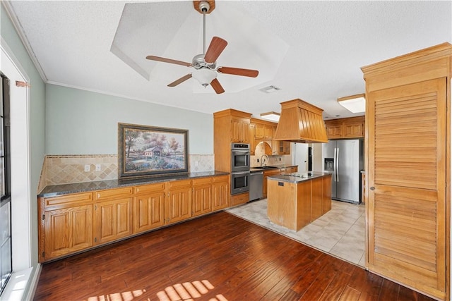 kitchen with a center island, sink, decorative backsplash, light wood-type flooring, and stainless steel appliances